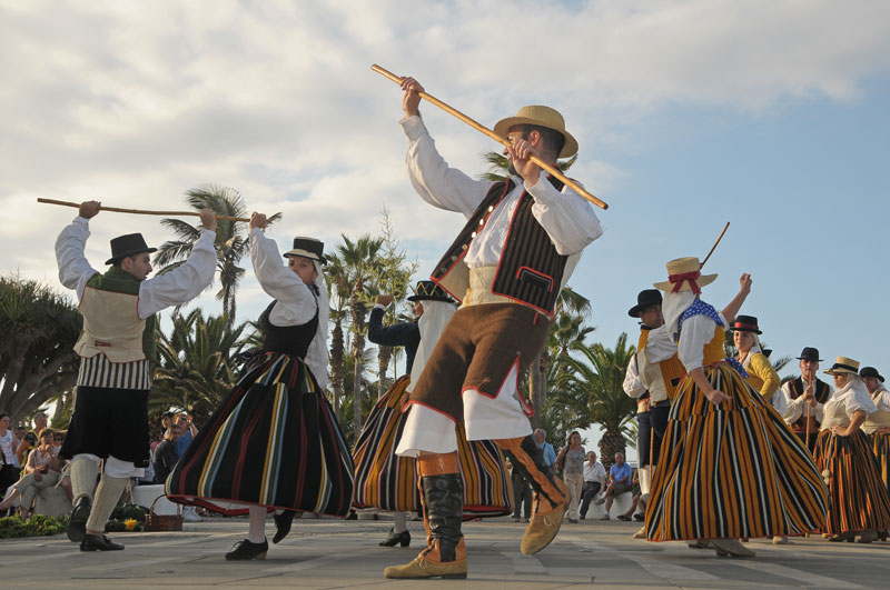 Un groupe de personnes vêtues de costumes traditionnels canariens dansent des danses traditionnelles.