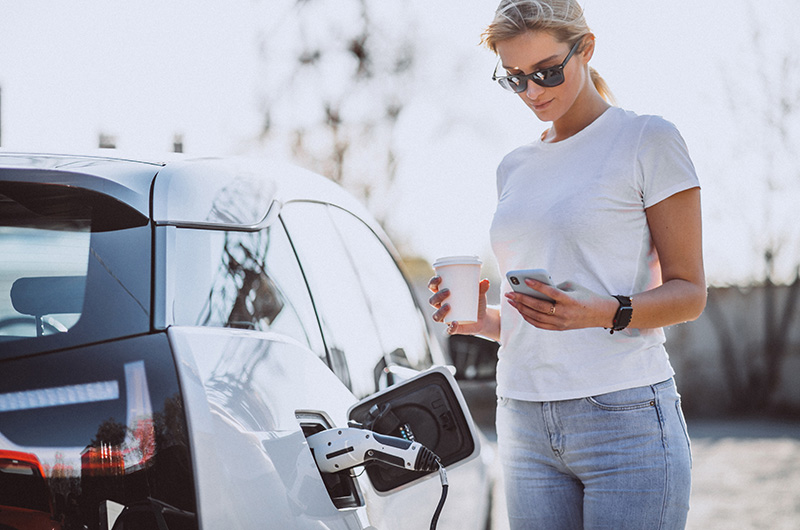 Une femme rechargeant une voiture électrique dans une station-service