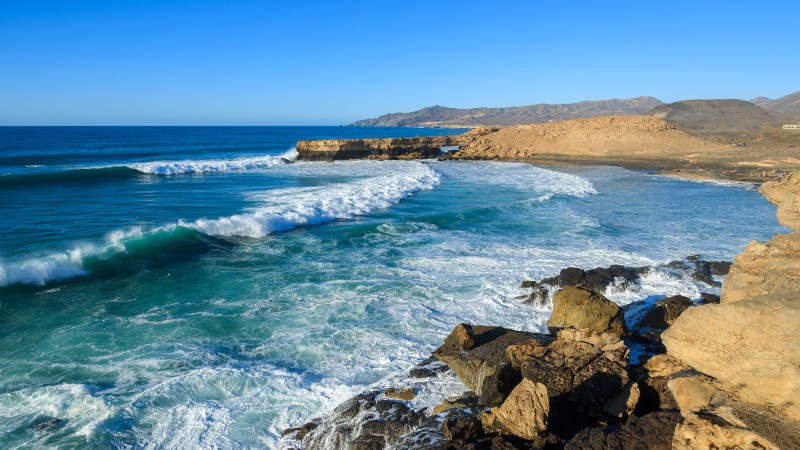 Panorama de la plage de La Pared à Fuerteventura avec une forte houle et des falaises rocheuses en arrière-plan, idéale pour les surfeurs expérimentés.